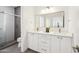 Elegant bathroom featuring double sink, modern fixtures, white cabinetry, and tiled shower with glass door at 5537 E Earll Dr, Phoenix, AZ 85018