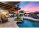 Beautiful backyard pool with waterfall feature, fireplace, and lots of seating under a pink and blue sunset at 6701 N Scottsdale Rd # 26, Scottsdale, AZ 85250
