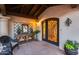 Beautiful arched front door, with decorative ironwork, and a welcoming tiled porch with seating and greenery at 6701 N Scottsdale Rd # 26, Scottsdale, AZ 85250