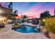 Backyard swimming pool with rock waterfall, lounge chairs, and an outdoor kitchen/barbecue area for entertaining at 6701 N Scottsdale Rd # 26, Scottsdale, AZ 85250