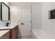 Elegant bathroom featuring wood vanity, a modern vessel sink, with a shower-over-tub and white-tiled walls at 7179 W Surrey Ave, Peoria, AZ 85381