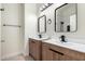 Contemporary double vanity bathroom with sleek black fixtures and modern lighting, leading to a tiled shower at 7179 W Surrey Ave, Peoria, AZ 85381