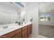 Bathroom with double sinks and wood cabinets, featuring natural light and a large mirror at 7577 S Towel Creek Dr, Gold Canyon, AZ 85118