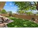Relaxing backyard with artificial grass, stone patio, privacy wall, and mature tree at 8259 W Carol Ave, Peoria, AZ 85345