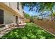 Well-maintained backyard with artificial grass, stone patio, privacy wall, and mature trees at 8259 W Carol Ave, Peoria, AZ 85345
