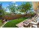 Inviting backyard featuring artificial turf, a stone patio, and a lush green border for added privacy at 8259 W Carol Ave, Peoria, AZ 85345