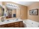 Well-lit bathroom with a double vanity and a separate soaking tub at 8259 W Carol Ave, Peoria, AZ 85345