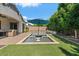 Lush backyard oasis with a sparkling pool, integrated loungers, covered patio, and mature trees at 883 E Hampton Ln, Gilbert, AZ 85295