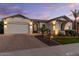 A single-Gathering home featuring a three-car garage, lush landscaping, and an extended paver driveway at 883 E Hampton Ln, Gilbert, AZ 85295