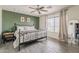 Well-lit bedroom features wood-look tile flooring, ceiling fan, and a black wrought iron bed frame at 8912 N Johnson Ct, Maricopa, AZ 85139