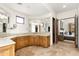 Spacious bathroom with double sinks, warm wood cabinets, travertine floors, and a view to the adjacent bedroom at 10010 E Blue Sky Dr, Scottsdale, AZ 85262