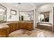 A bathroom with a double sink, wood cabinets, travertine floors and large soaking tub near a window at 10010 E Blue Sky Dr, Scottsdale, AZ 85262