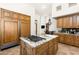 Spacious kitchen offers custom wood cabinetry, stainless appliances, a large kitchen island, and stone tile flooring at 10010 E Blue Sky Dr, Scottsdale, AZ 85262