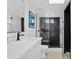 Modern bathroom with glass-enclosed shower, black herringbone tile accent wall, and contrasting white vanity at 101 E Linger Ln, Phoenix, AZ 85020