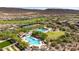 Aerial shot of pools, tennis courts, and a green common area in a desert community at 12725 W Forest Pleasant Pl, Peoria, AZ 85383