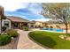 Lush backyard featuring a pool, green turf, and a winding brick walkway at 12725 W Forest Pleasant Pl, Peoria, AZ 85383