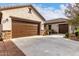 Expansive driveway leads to a spacious garage, complemented by a stucco exterior and well-manicured landscaping at 12725 W Forest Pleasant Pl, Peoria, AZ 85383