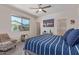 Cozy bedroom with a large window, ceiling fan, and desert themed artwork at 18388 W Ida Ln, Surprise, AZ 85387