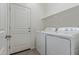 Well-lit laundry room with white washer, dryer, storage shelf, and exterior door at 18388 W Ida Ln, Surprise, AZ 85387