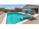 Inviting backyard pool with an umbrella, lounge chairs, and desert plants for serene outdoor enjoyment at 18388 W Ida Ln, Surprise, AZ 85387