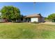 Spacious backyard featuring a covered patio, mature trees, and green lawn at 18842 N Lakeforest Dr, Sun City, AZ 85373