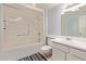 Bright bathroom featuring white tiling, a tub with shower and vanity with sink at 18842 N Lakeforest Dr, Sun City, AZ 85373