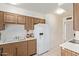 Functional kitchen featuring wood cabinetry, white appliances, and ample counter space at 18842 N Lakeforest Dr, Sun City, AZ 85373