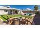Lush backyard with artificial grass, a fire pit, covered patio, swimming pool, and lounge chairs at 19414 N 3Rd Ave, Phoenix, AZ 85027