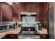 Close-up of kitchen area with stainless steel stove, wooden cabinets, and tiled backsplash at 19414 N 3Rd Ave, Phoenix, AZ 85027