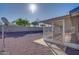 View of the gravel backyard, enclosed patio, and partial view of the neighborhood beyond the block fence at 19849 N 33Rd Ave, Phoenix, AZ 85027