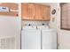 Functional laundry room with wood cabinets and side by side washer and dryer at 201 S Greenfiled Rd -- # 199, Mesa, AZ 85206