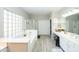 Bright bathroom featuring a soaking tub, separate shower, double vanity, and wood-look tile flooring at 2224 W Olive Way, Chandler, AZ 85248