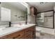 Bathroom featuring double sinks, wood cabinets, white countertop, modern fixtures, and a glass shower door at 3028 W Parkside Ln, Phoenix, AZ 85027