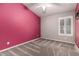 Bedroom featuring a ceiling fan, neutral paint, a bright pink accent wall, and plush carpeting at 3028 W Parkside Ln, Phoenix, AZ 85027