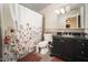 Bathroom with floral shower curtain, black vanity with granite top, and decorative tile backsplash at 327 E Monte Way, Phoenix, AZ 85042