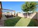 Backyard featuring a pergola-covered seating area, lush green lawn, and serene tree-lined backdrop at 36515 N Takota Trl, San Tan Valley, AZ 85140