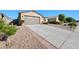 Low angle of concrete driveway leading to a two-car garage, framed by desert landscaping and a blue sky backdrop at 36515 N Takota Trl, San Tan Valley, AZ 85140