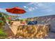 The backyard features a full outdoor kitchen and dining area with comfortable seating and an umbrella at 42311 W Good Vibrations Ln, Maricopa, AZ 85138