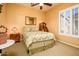 Comfortable bedroom featuring a queen bed, a desk, plantation shutters, and neutral-colored walls at 42311 W Good Vibrations Ln, Maricopa, AZ 85138
