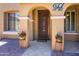 Charming covered entry with iron gate door, decorative planters, and welcoming exterior at 42311 W Good Vibrations Ln, Maricopa, AZ 85138