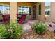 Inviting covered patio with red cushioned chairs, stone flooring, and lush rose bushes, perfect for outdoor relaxation at 42311 W Good Vibrations Ln, Maricopa, AZ 85138