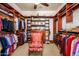Spacious walk-in closet featuring custom shelving, hanging rods, a ceiling fan, and a comfortable chair at 42311 W Good Vibrations Ln, Maricopa, AZ 85138