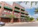 A brick building featuring green balconies and brown garage doors on a bright day at 424 S 2Nd St # 306, Phoenix, AZ 85004