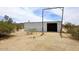 Metal outbuilding, framed entrance and gravel surrounded by desert landscaping at 53404 W Candlelight Rd, Maricopa, AZ 85139