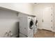 Functional laundry room with tile flooring, modern washer and dryer, and built-in shelving at 5446 S Sandstone Ct, Gilbert, AZ 85298