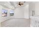 Spacious bonus room with neutral carpet, vaulted ceiling, fan, bright windows, and white staircase at 579 N Mondel Dr, Gilbert, AZ 85233