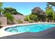 Backyard pool featuring a stone privacy wall, vibrant landscaping, and sunny ambiance at 6920 E Beverly Ln, Scottsdale, AZ 85254
