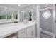 Bathroom featuring a large vanity with dual sinks, mirrors, and a glass enclosed shower with a patterned window at 7800 E Lincoln Dr # 2029, Scottsdale, AZ 85250