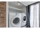 Bright laundry area with white washer and dryer, storage shelf, and stylish blue patterned curtain at 7800 E Lincoln Dr # 2029, Scottsdale, AZ 85250