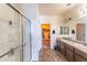 Well-lit bathroom featuring double sinks, granite countertops, and a glass shower at 8924 N 102Nd Ln, Peoria, AZ 85345